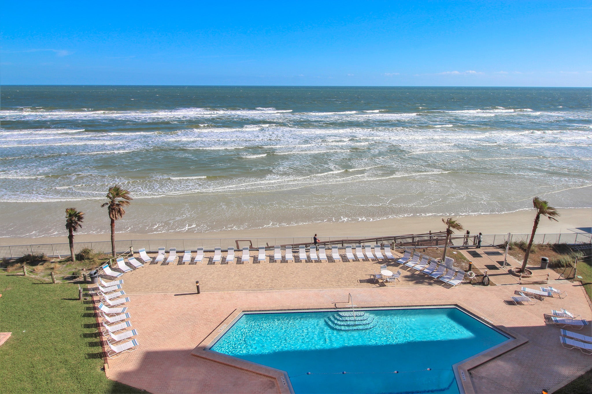 Balcony overlooks ocean and pools